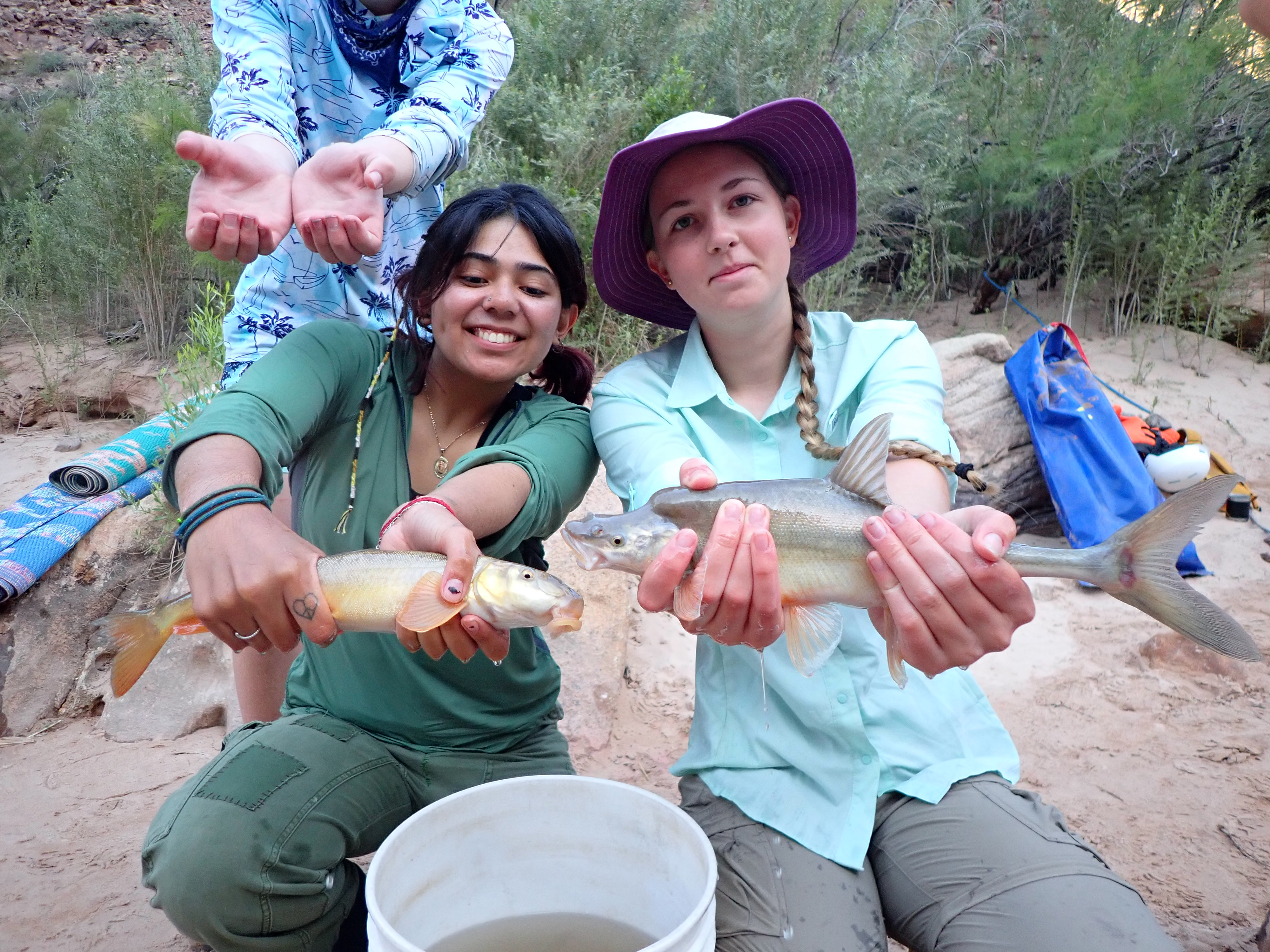 Two campers hold fish out towards the camera